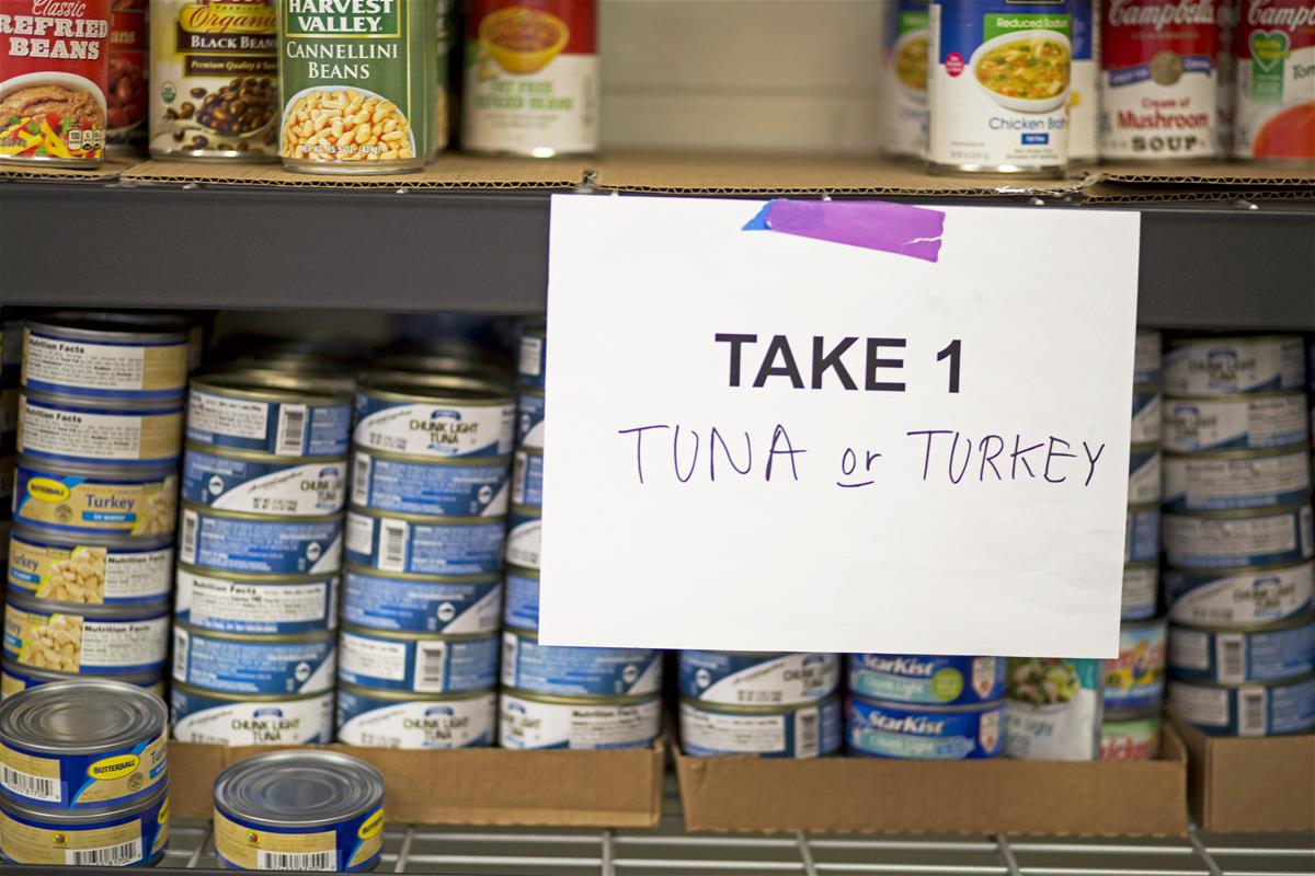 Canned good offerings Shelves with cans of tuna, turkey, and vegetables, with sign reading