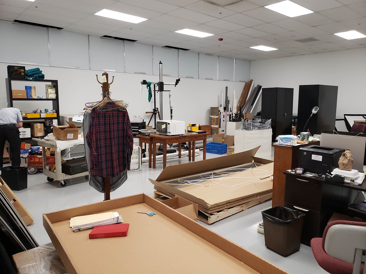 Unpacking and rearranging the new Photo Studio Room cluttered with large boxes, furnishings, and other items