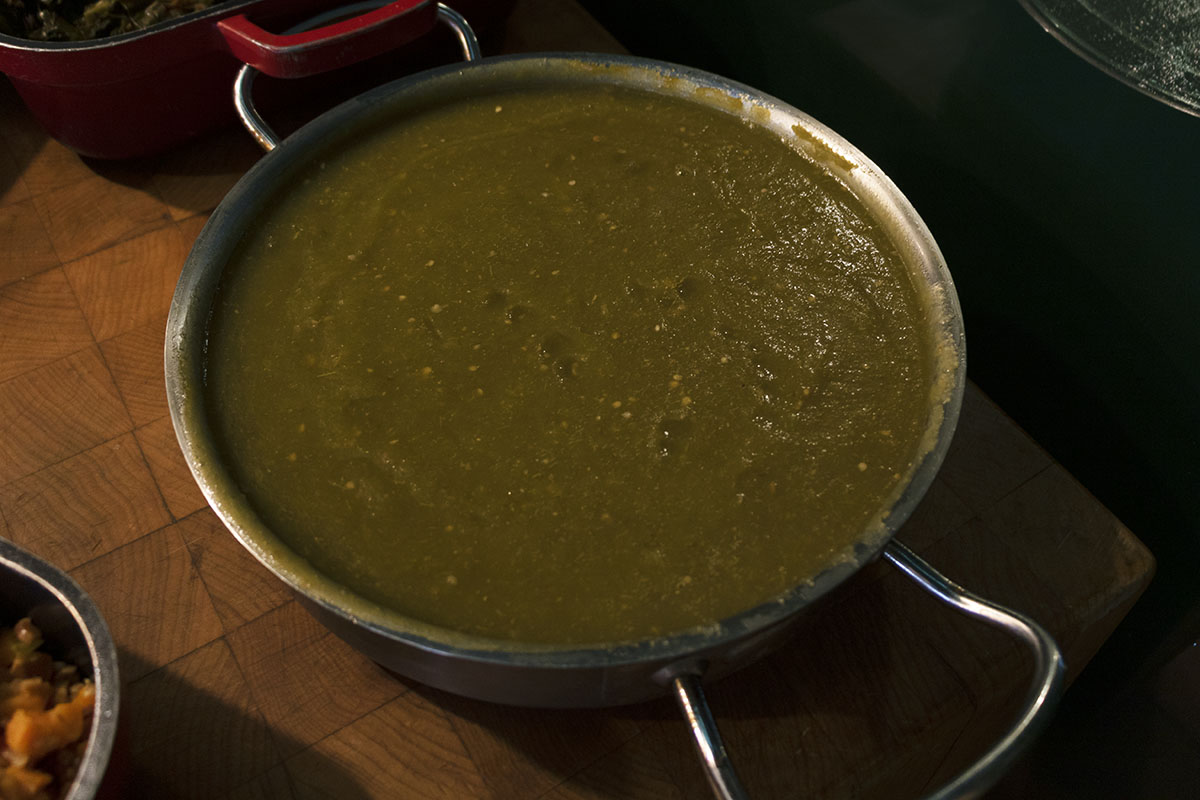 Green Tomato Chili Sauce Silver dish with handles, containing green sauce, sitting on butcher block