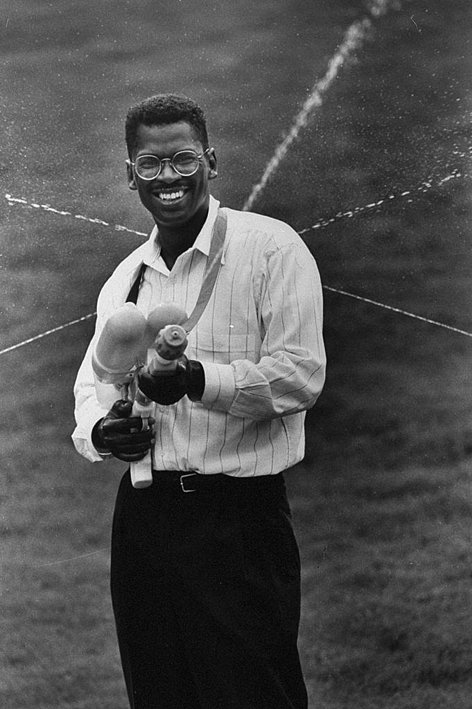Lonnie Johnson, Inventor of the Super Soaker African American man wearing round glasses smiles and points large water gun toward camera
