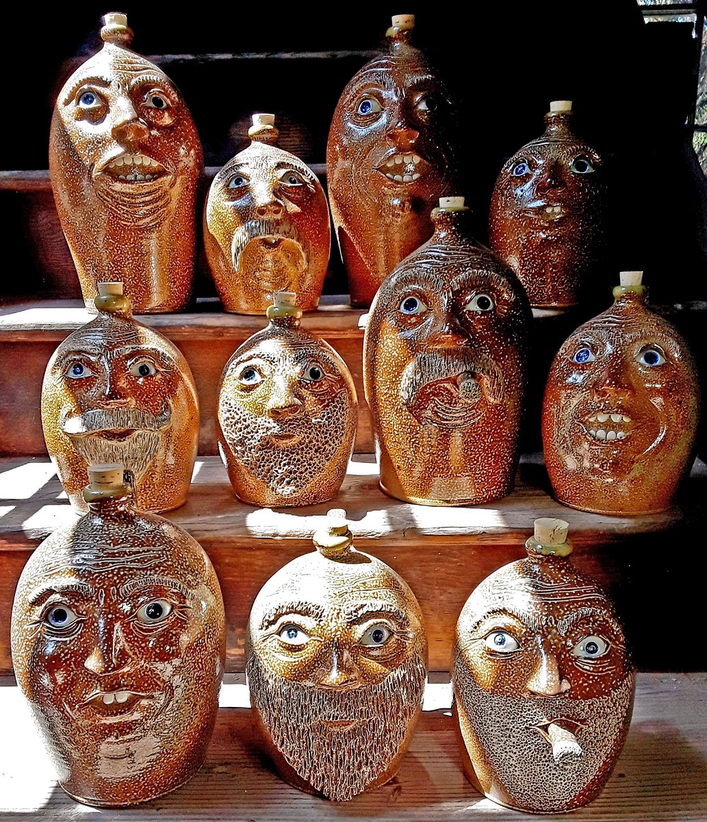 Eight orange pottery jugs topped with corks feature a variety of whimsical faces