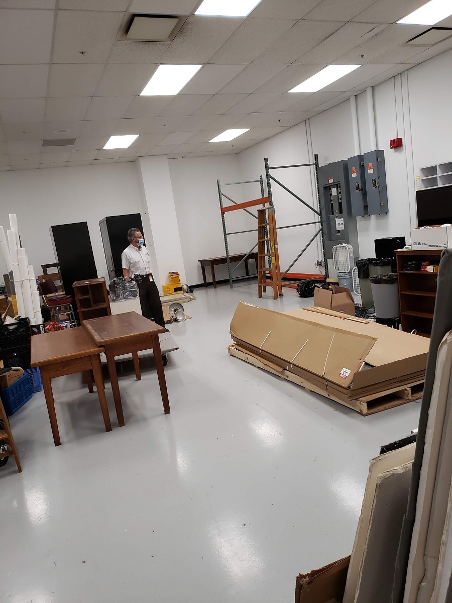 Unloading and organizing our equipment in the new studio Man stands among furniture and supplies in large open room