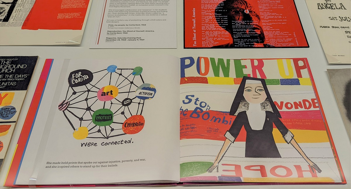 Make Meatballs Sing: The Life and Art of Corita Kent Colorful picture book with text and images open among other material in a display case