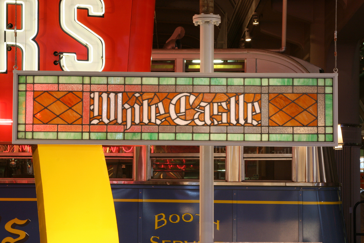 Stained glass sign in red, orange, and green, with white text 