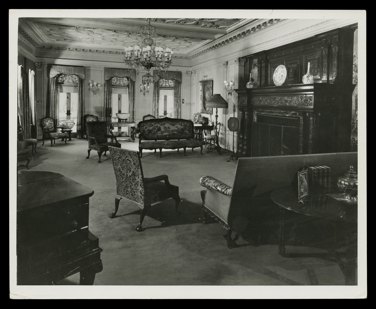 Living Room at Fair Lane, Home of Henry Ford, March 1916 Black-and-white photograph of room with large, dark fireplace and ornate ceilings and furniture