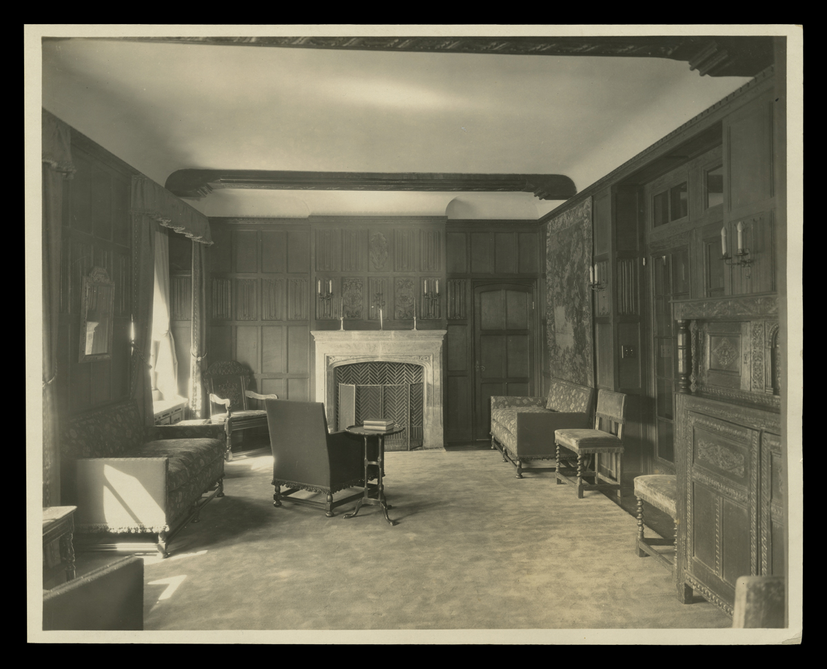 Paneled room with fireplace, couches, chairs, and other furniture