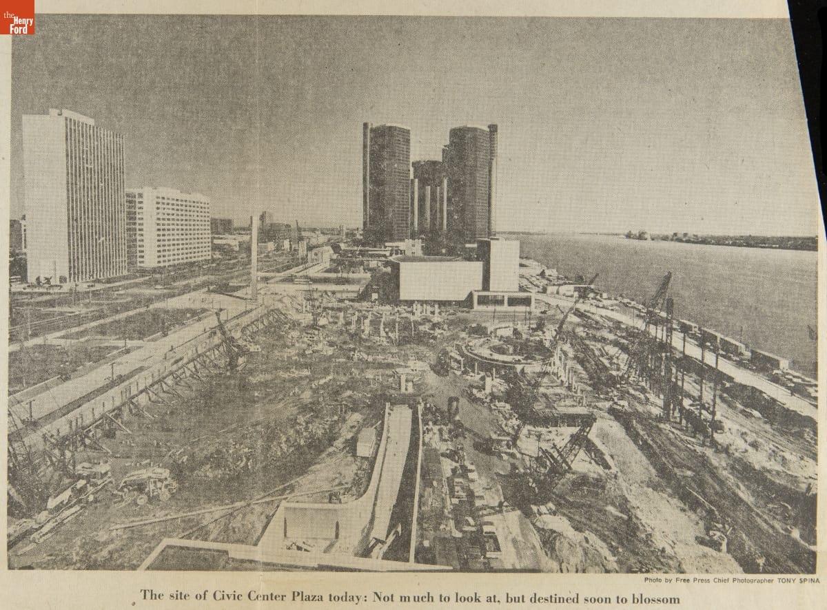 Detroit Free Press Article, Image of construction site by river with tall buildings behind and to the side of it