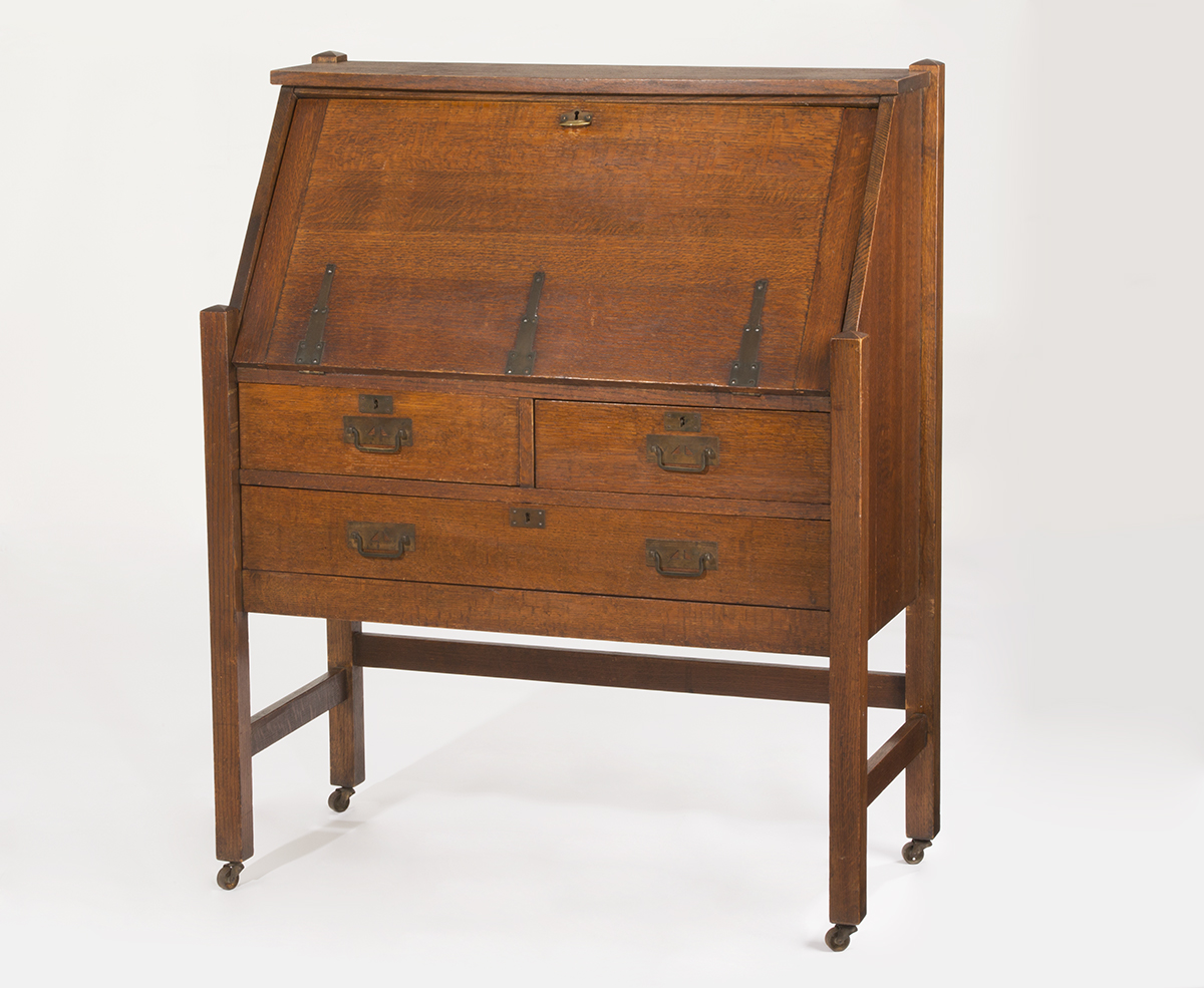 Wooden furniture on casters with drawers topped by a slanted flat surface (that presumably folds down to form a desk)