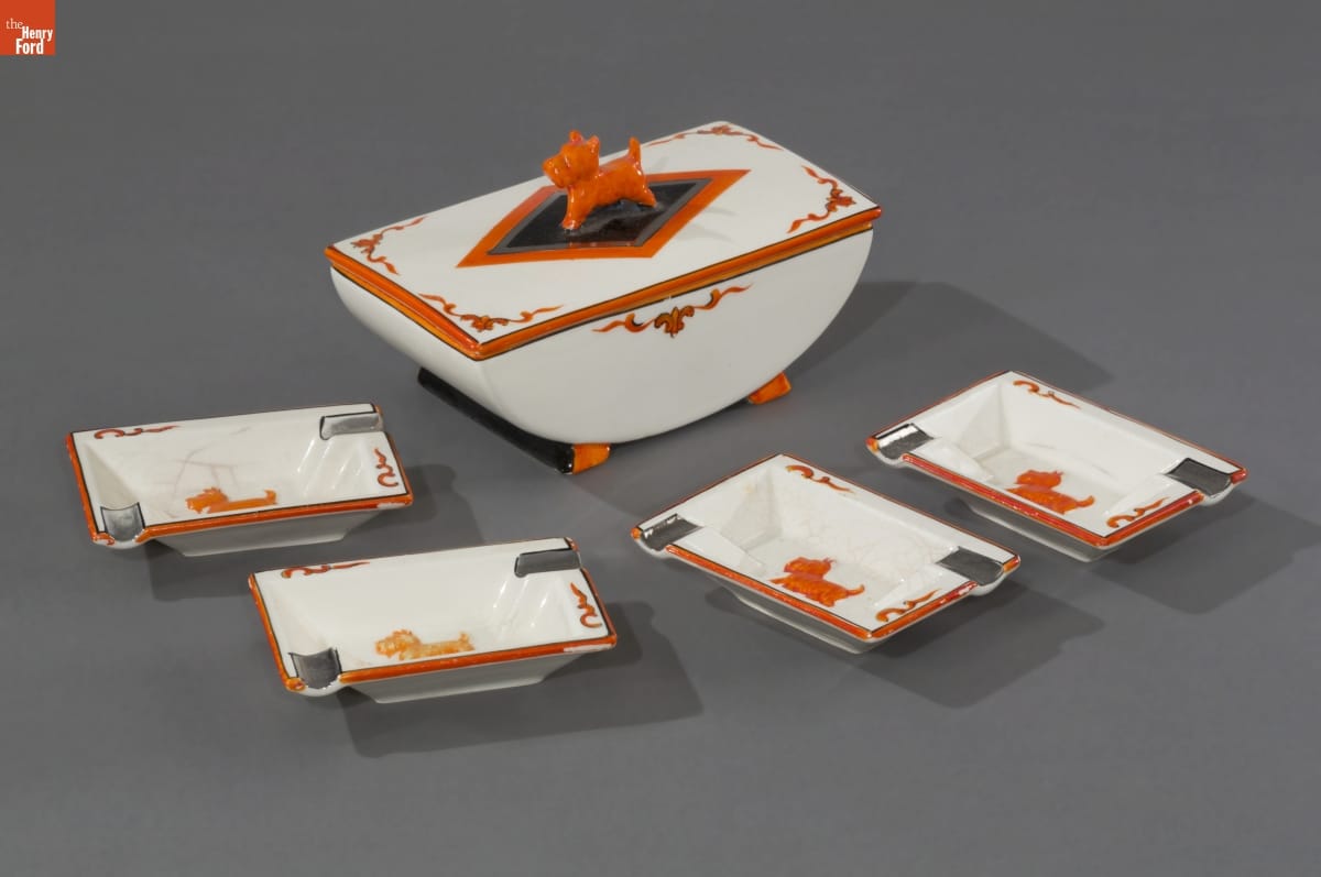 White arc-shaped dish with orange decorations and an orange Scottie dog on top, sitting with four small rectangular dishes with orange Scottie dogs inside the bottom