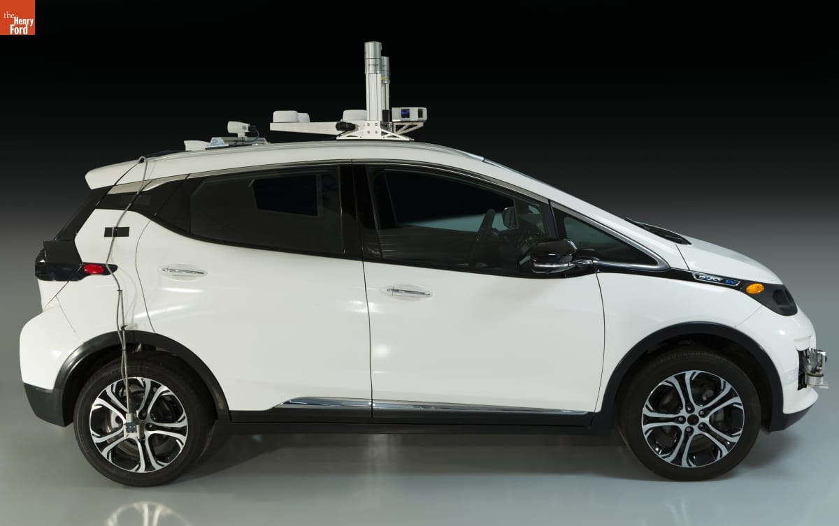 Side view of compact white car with equipment on top and wires dangling down side