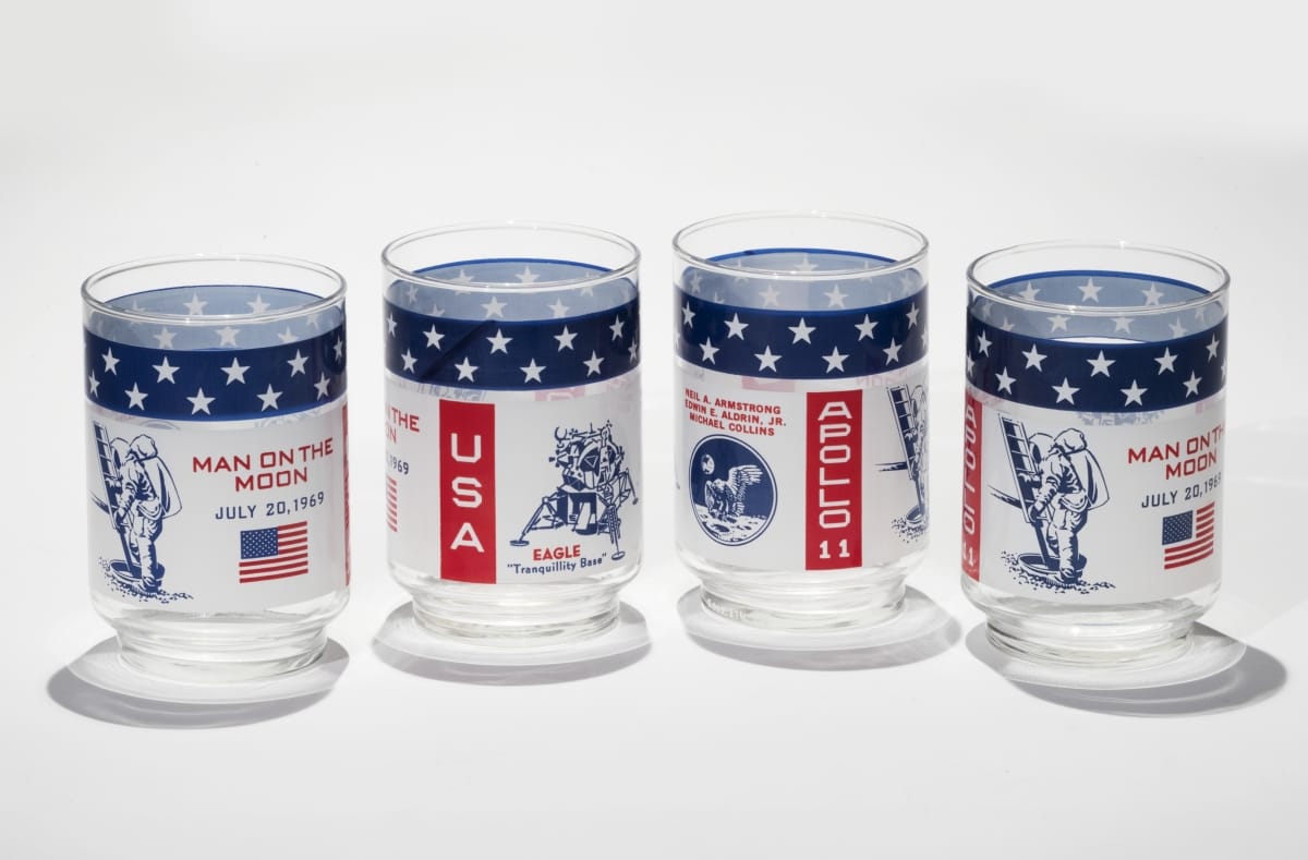 Set of Tumblers Commemorating the First Moon Landing, circa 1969 Four clear glasses with white, red, and blue designs, text, and spaceflight-related images