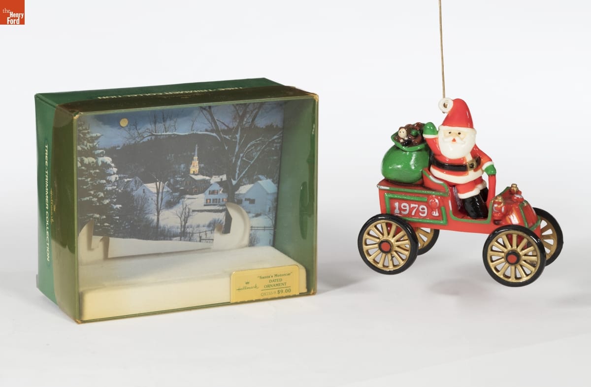 Ornament of Santa sitting in an old-fashioned open red car with 