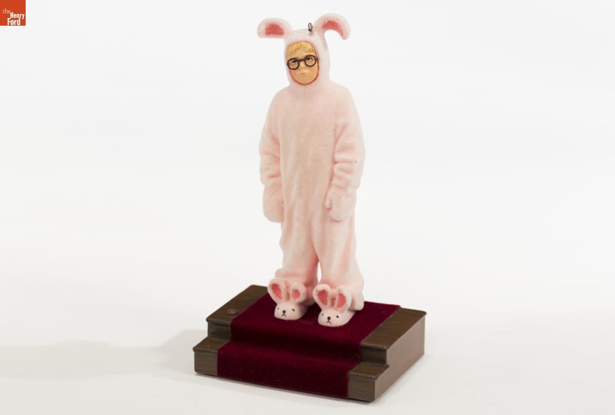 Christmas ornament depicting a boy wearing glasses in a pink full-body bunny suit