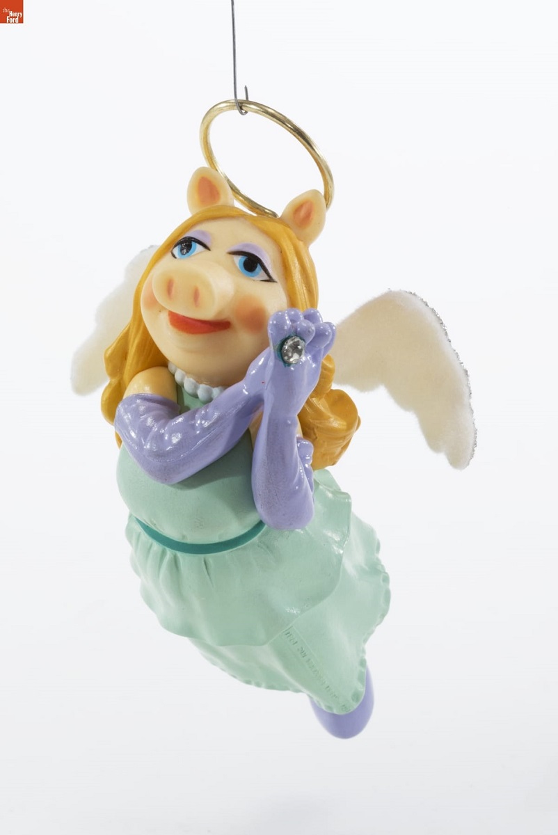 Hallmark Christmas ornament of pig in blue gown with purple shoulder-length gloves, blonde hair, and pink angel wings