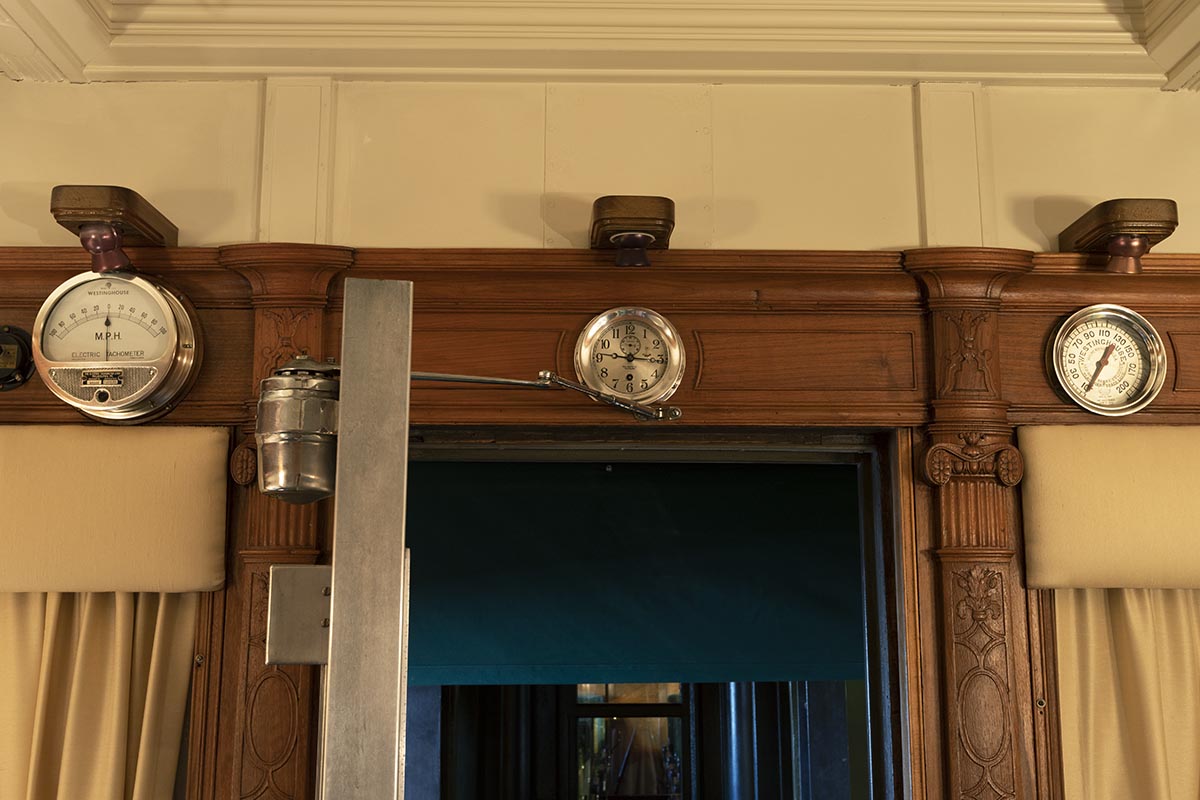 Henry Ford's Private Railroad Car Part of interior wall with wood paneling, doorway, and three silver clocks/dials