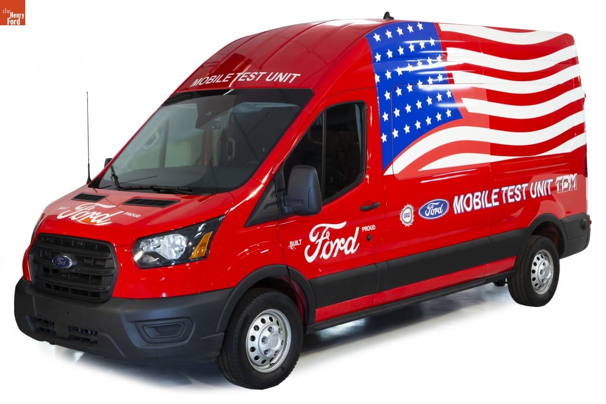 Tall red van with text on front and side and American flag on side
