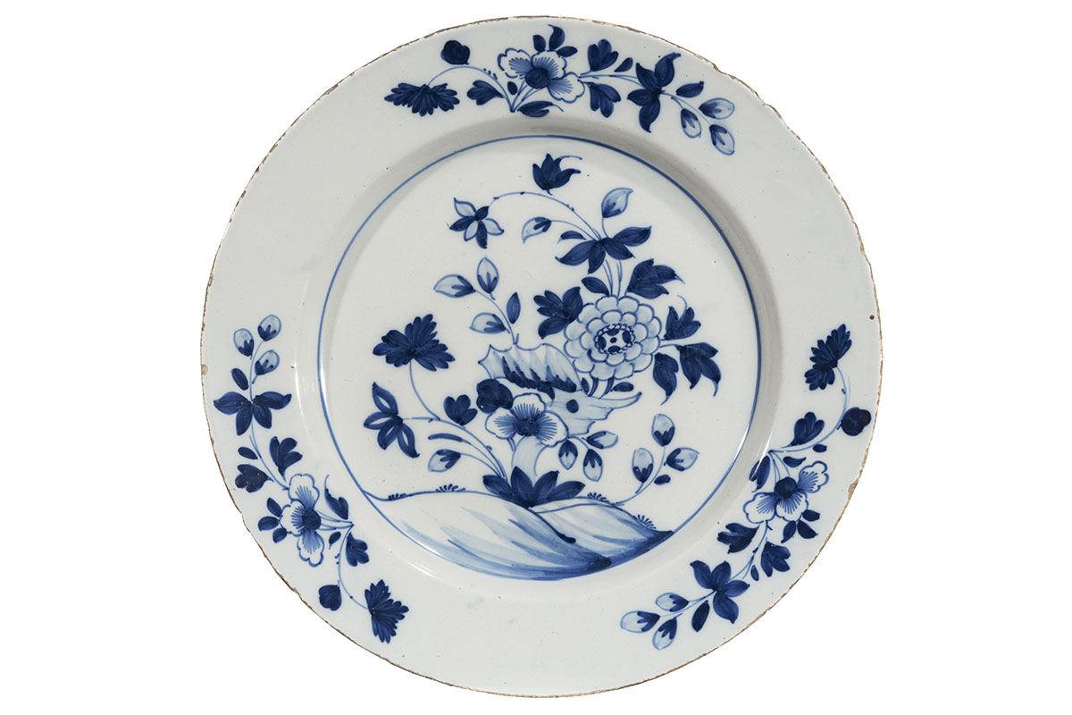 Plate, circa 1700 White plate with blue floral decorations in three places on rim and large blue floral decoration in center