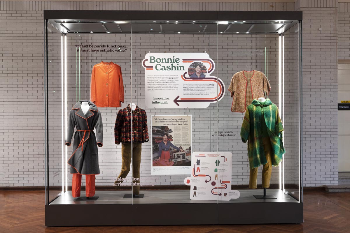 What We Wore: Bonnie Cashin Large glass display case containing mannequins wearing clothing, signs and graphics, and additional hung clothing