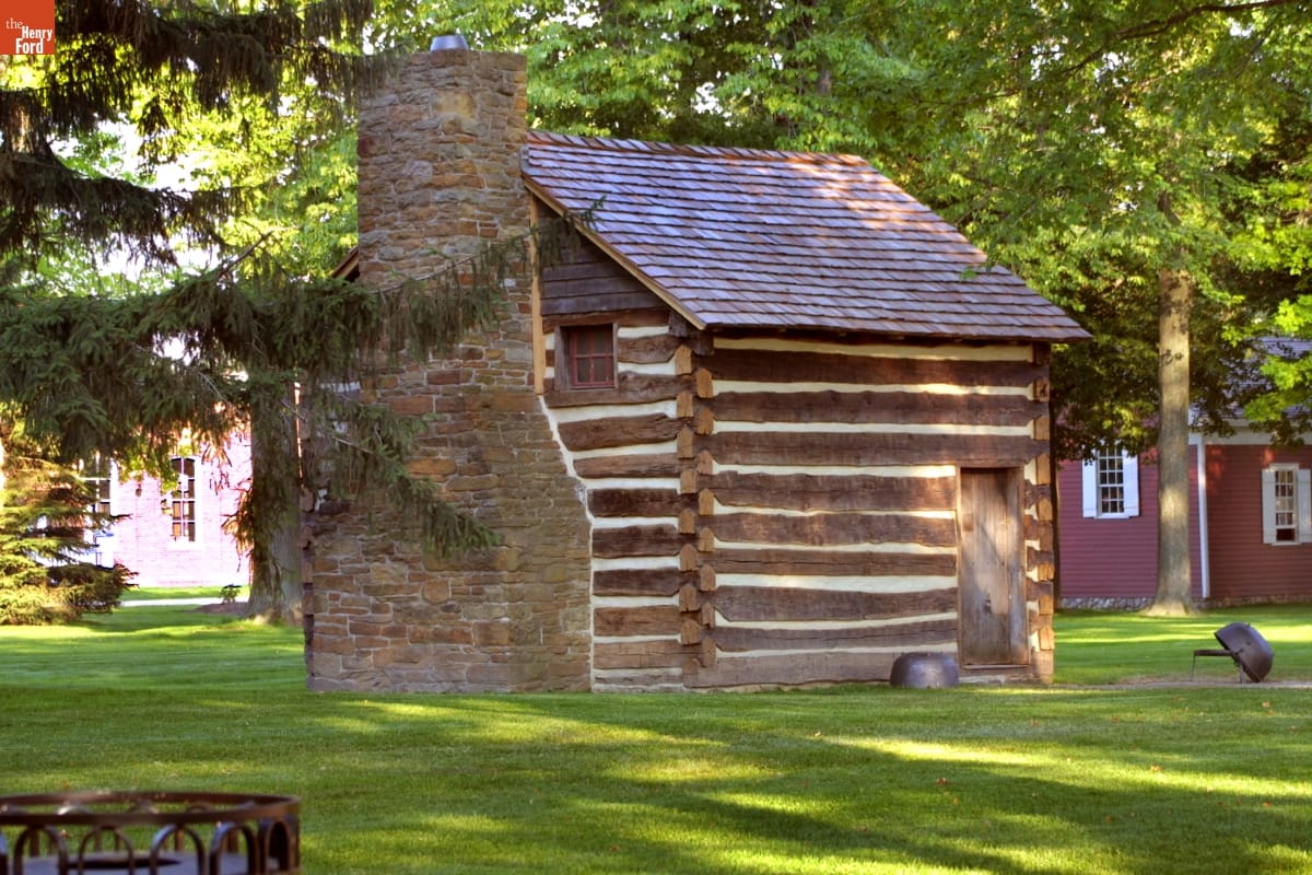 William Holmes McGuffey Birthplace Small log cabin with shingled roof and stone fireplace, surrounded by grass and other buildings