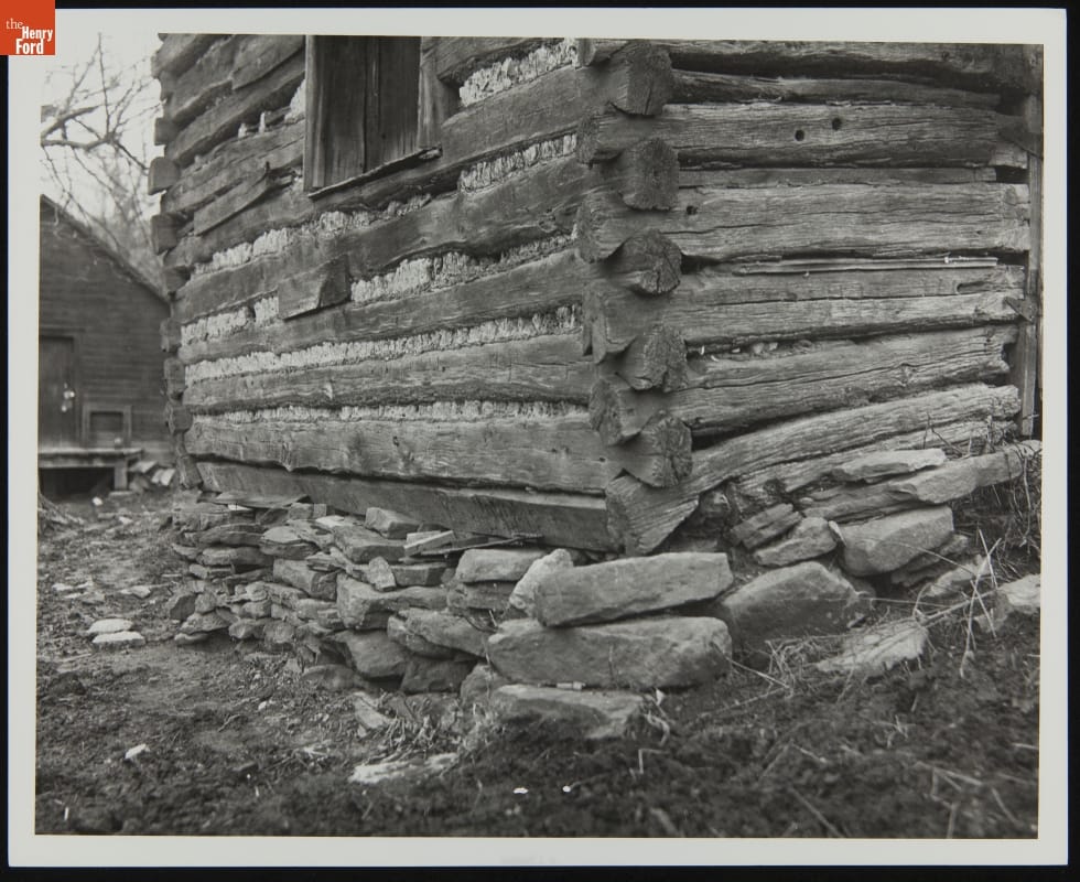 Close-up photo of corner of log cabin on stone foundation