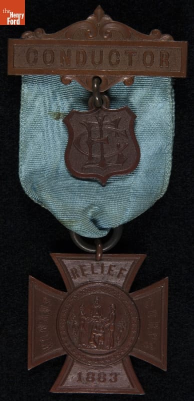 Woman's Relief Corps (W.R.C.) Conductor Badge, 1883-1920 Metal and fabric badge, with cross-shaped piece containing text underneath a fabric arch