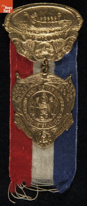 Grand Army of the Republic (G.A.R.) 1914 National Encampment in Detroit, Michigan Badge Red, white, and blue ribbon behind gold medallion with intricate pattern; also contains text