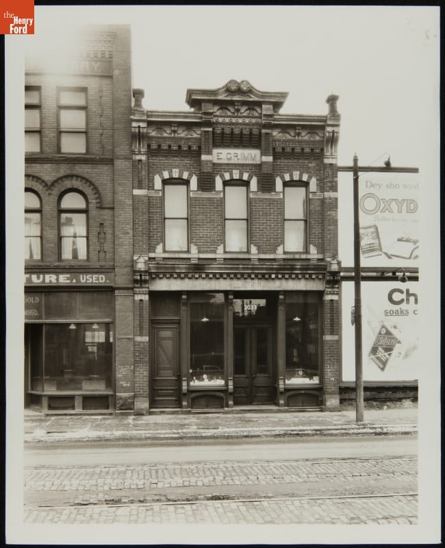 Black-and-white photograph of two-story brick building with decorative windows and cornice