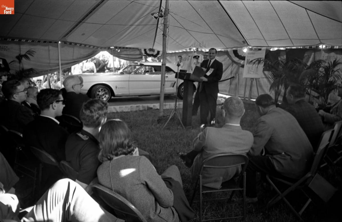 thf264132 Lee Iacocca introducing the Mustang II concept car at Watkins Glen in October 1963 in a tent.