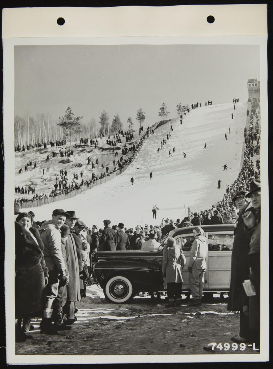8th Annual Kiwanis Ski Club Tournament, Iron Mountain, Michigan, February 1941 People on steep, snow-covered ski slope, with crowds on either side and more crowds and a car in the foreground