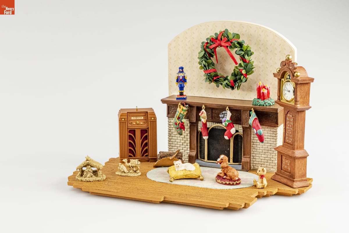 Vignette of part of room, with stockings hung from mantel, a Christmas wreath above the fireplace, and a dog and cat lying on pet beds, as well as other furniture