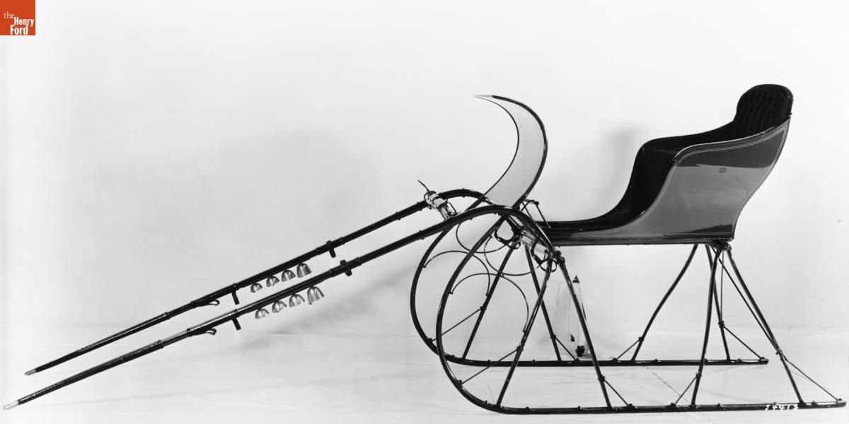Open sleigh with curving lines and bells attached to harness posts