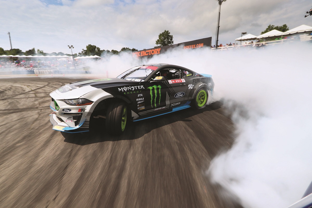 Vaughn Gittin, Jr.’s Mustang RTR race car Gray and white race car turns on racetrack and trails smoke