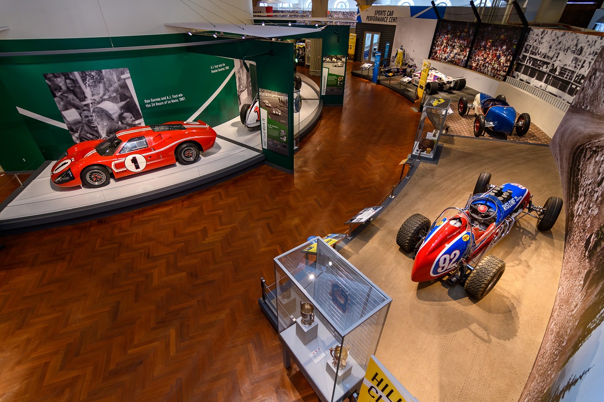 Aerial shot of museum exhibit featuring cars, along with other artifacts and graphic panels with images and text